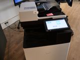 une imprimante posée sur un bureau, devant un écran