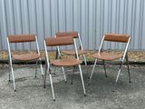 three brown chairs sitting next to each other in front of a metal wall