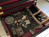 une boîte à outils rouge contenant des outils, posée sur un sol carrelé