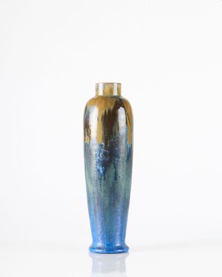 un vase bleu et or posé sur une surface blanche