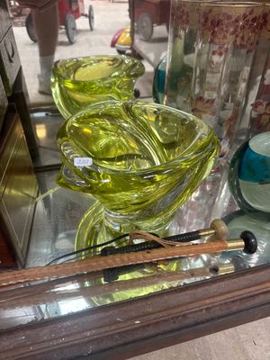 a glass display case filled with green vases and other glassware