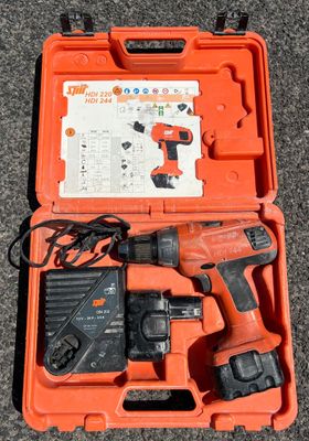 an orange box with a corded drill and a charger in it