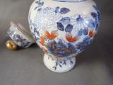 a blue and white vase with flowers on it and a gold bell