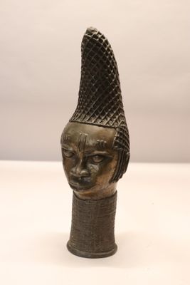 bronze head of a woman with a hat on her head