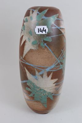 a brown vase with leaves on it on a white surface