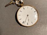 a small pocket watch with a key hanging from it ' s chain