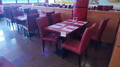 tables and chairs in a restaurant with a refrigerator in the background