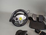 a steering wheel, pedals, and a mouse on a table