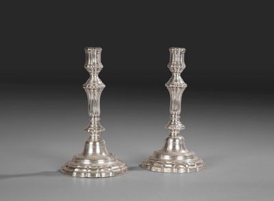 une paire de bougeoirs en argent sur fond gris
