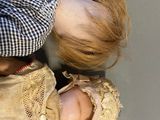 a woman holding a doll in her arms and a baby in her lap