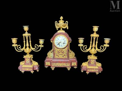 trois bougeoirs dorés et rouges et une horloge sur fond noir