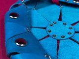 a blue leather purse with rivets on it on a pink surface