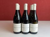 trois bouteilles de vin sont posées sur une table devant un mur rouge
