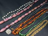 several different colored beads and chains on a black surface