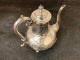 a silver tea pot sitting on a black surface