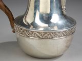 a silver pitcher with a wooden handle sitting on a table