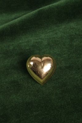 broche en forme de cœur dorée sur fond de velours vert