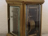 a small brass clock with a glass case on a table