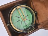 a wooden box with a green compass inside of it