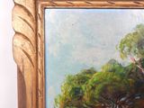 an oil painting of a tree in a golden frame on a white wall