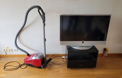 une photo représentant un téléviseur et un aspirateur posés sur un parquet