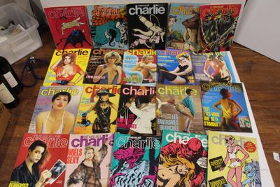 beaucoup de magazines posés sur une table, à côté d'une bouteille de vin