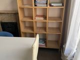 a white table with a white chair in front of a bookshelf
