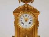 une horloge en or surmontée d'un oiseau