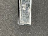 a silver dog tag on a chain on a black surface