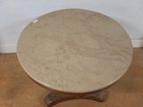 a marble top table with a wooden base on a tile floor