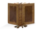 un vieux livre surmonté d'un pompon, posé sur une surface blanche
