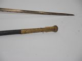 pair of old swords on a white surface with a black handle