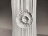 a white sculpture of a doughnut on a wooden block