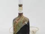a black bird sitting on top of a glass bottle