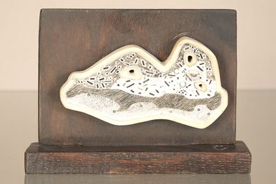 une sculpture en céramique représentant un oiseau, posée sur un socle en bois