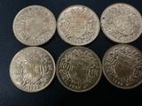 six different british coins are shown in a row on a black surface