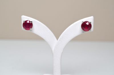 une paire de boucles d'oreilles à clous en rubis, présentée sur un socle blanc