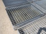 une grille métallique posée au sol à côté d'une autre grille métallique