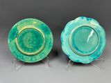 une paire d'assiettes vertes et bleues à bordure dorée, posées sur des socles