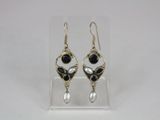 a pair of black and white earrings on a clear display case
