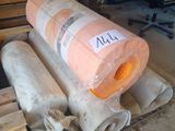 several rolls of wood sit on top of pallets in a warehouse