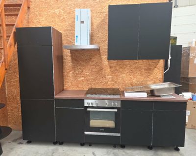 une photo d'une cuisine avec des placards noirs et une cuisinière