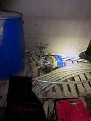 une valise rouge posée sur une palette à côté d'un fût bleu