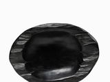 a close up of a black oval stone on a white surface