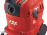 un aspirateur rouge et noir muni de roulettes, sur fond blanc