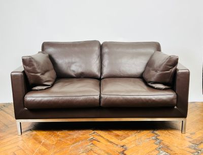 un canapé en cuir marron posé sur un parquet en bois massif