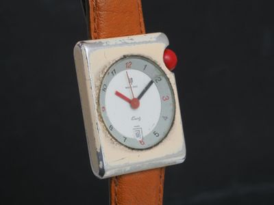 une petite montre carrée avec un cadran blanc et un bracelet en cuir marron