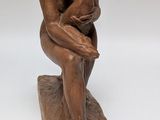 statue of a man sitting on a rock with his hands on his knees