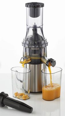 un extracteur de jus à côté duquel se trouve un verre de jus d'orange