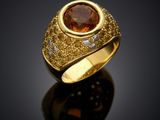 a close up of a gold ring with a large brown stone